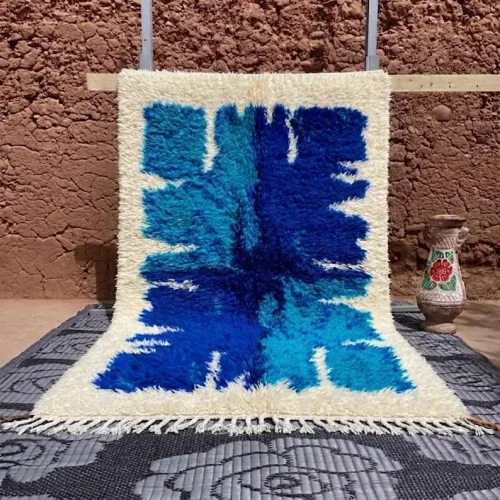 Authentic hand-knotted blue Moroccan rug hanging on a traditional wooden loom